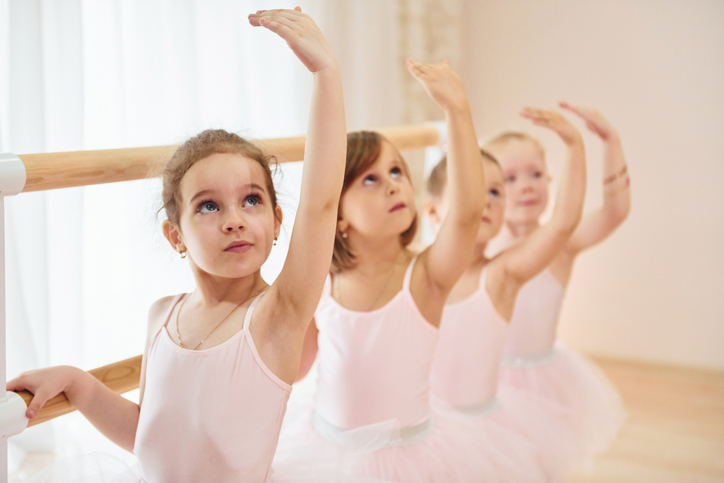 Little ballerinas preparing for performance by practicing dance moves.